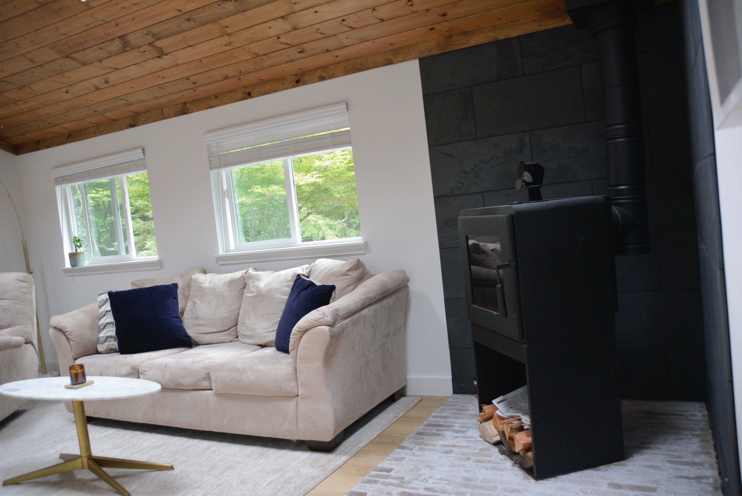 Beige couch next to black wood-burning fireplace