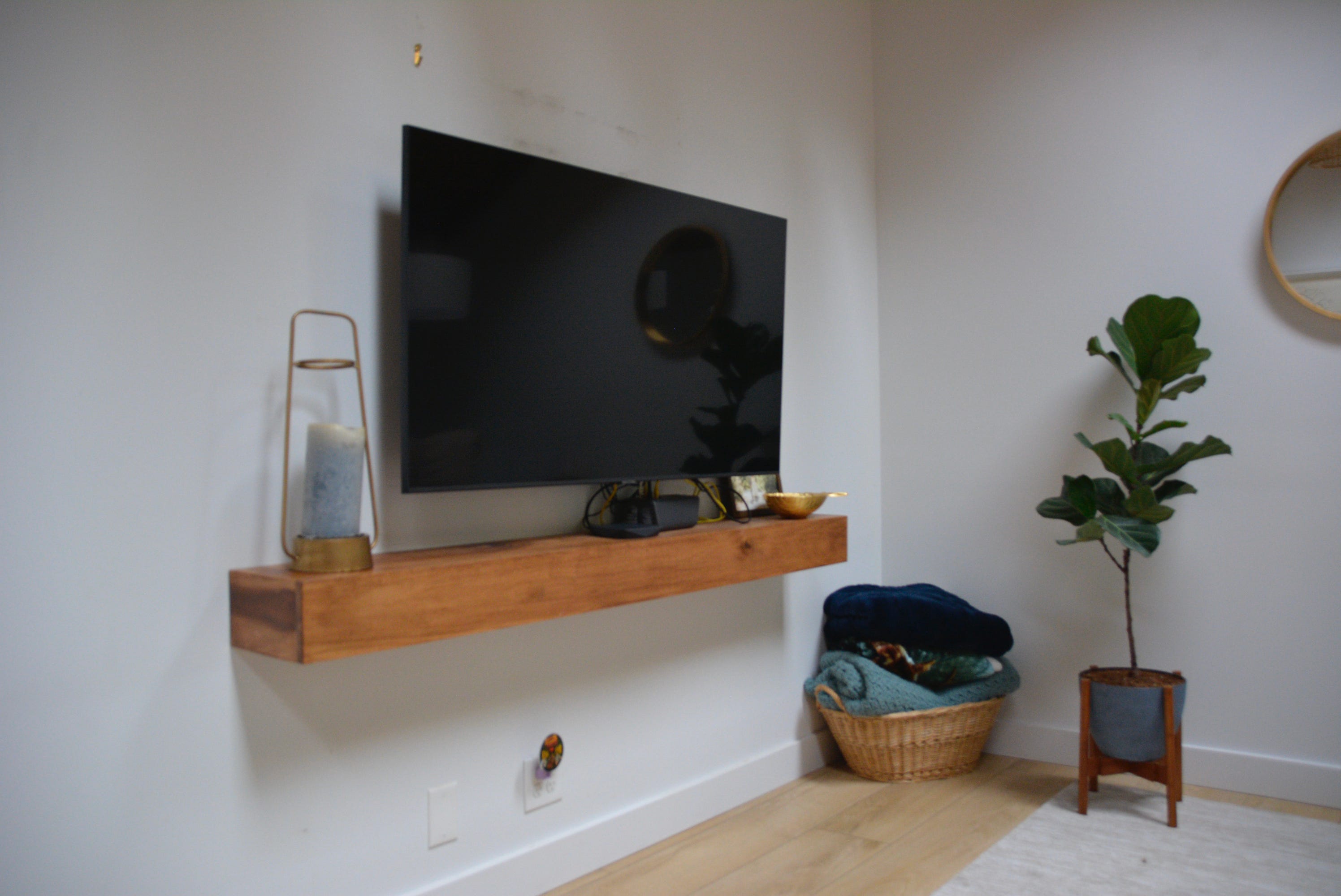 TV above wood ledge on white wall