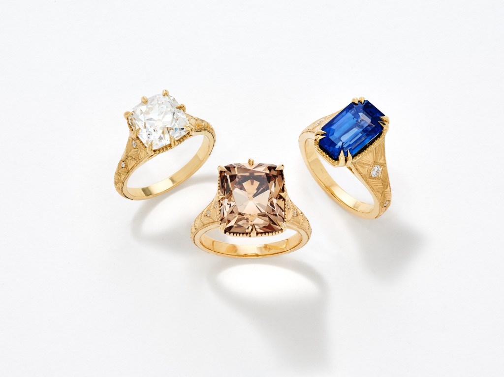 Three Gem Drop Kindred & Jogani rings from Sotheby's, one with a white gem, one with a brown gem, and one with a blue gem.
