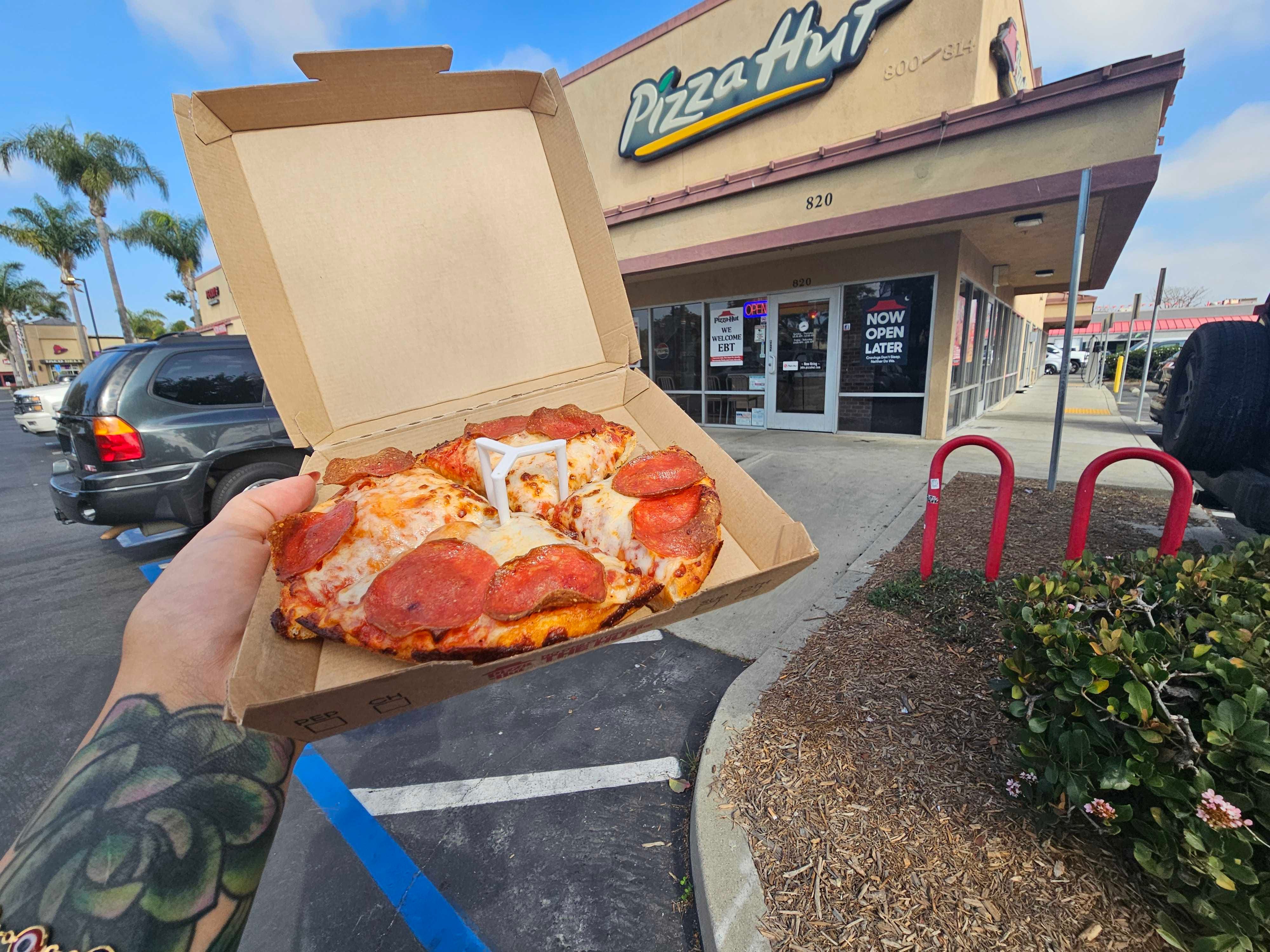 A close up of a personal pizza outside a Pizza Hut restaurant.