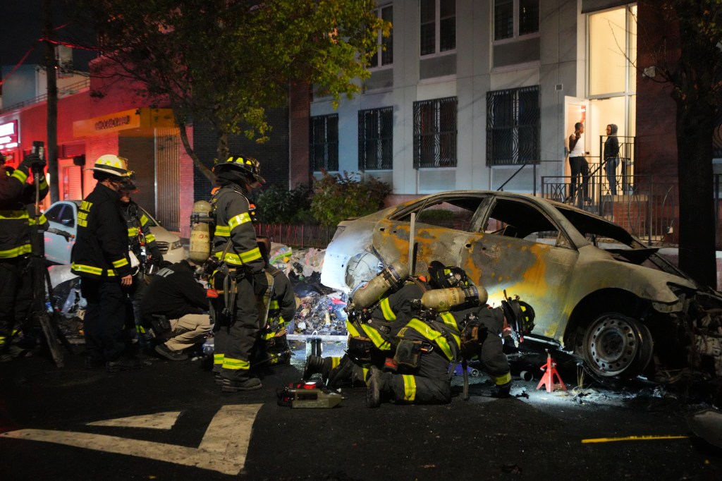 Firefighters respond to a car fire at night.