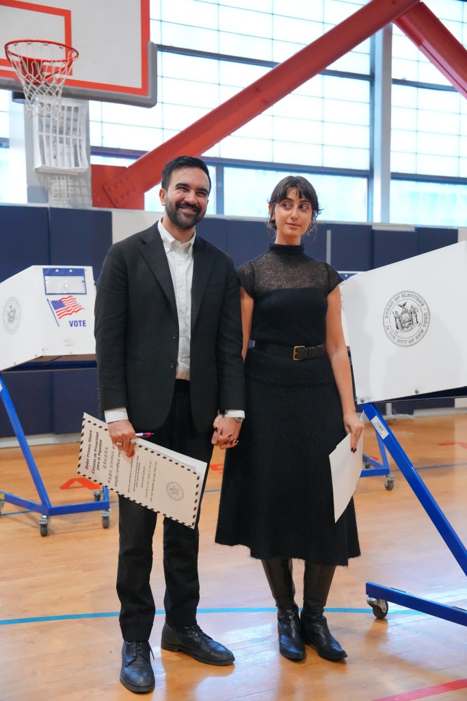 Zohran Mamdani and his wife, Rama Duwaji, standing with ballot materials at a polling place.