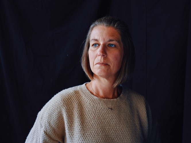 photo of woman wearing sweater looking to the left on dark background