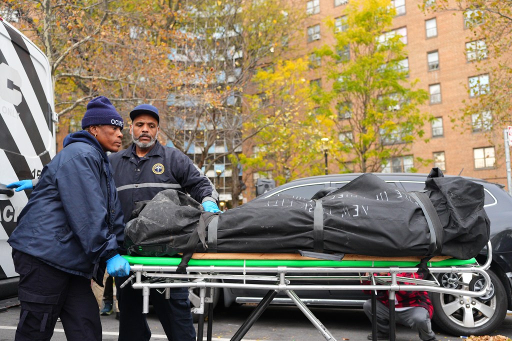 Two individuals from the Office of Chief Medical Examiner removing a body from an apartment building in the Bronx.
