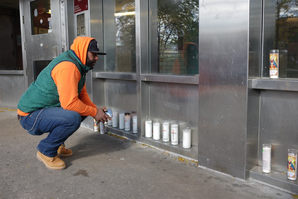 Felix Angomas pays his respects at a memorial with candles outside an apartment building.