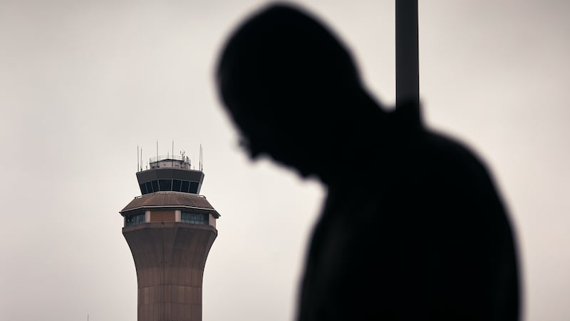A man stands outside Terminal C with the airport control tower in the background at Newark Liberty International Airport.