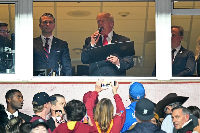 President Donald Trump, alongside Defense Secretary Pete Hegseth reads the oath for people reenlisting to the U.S. army as he attends the NFL game between the Washington Commanders and the Detroit Lions.