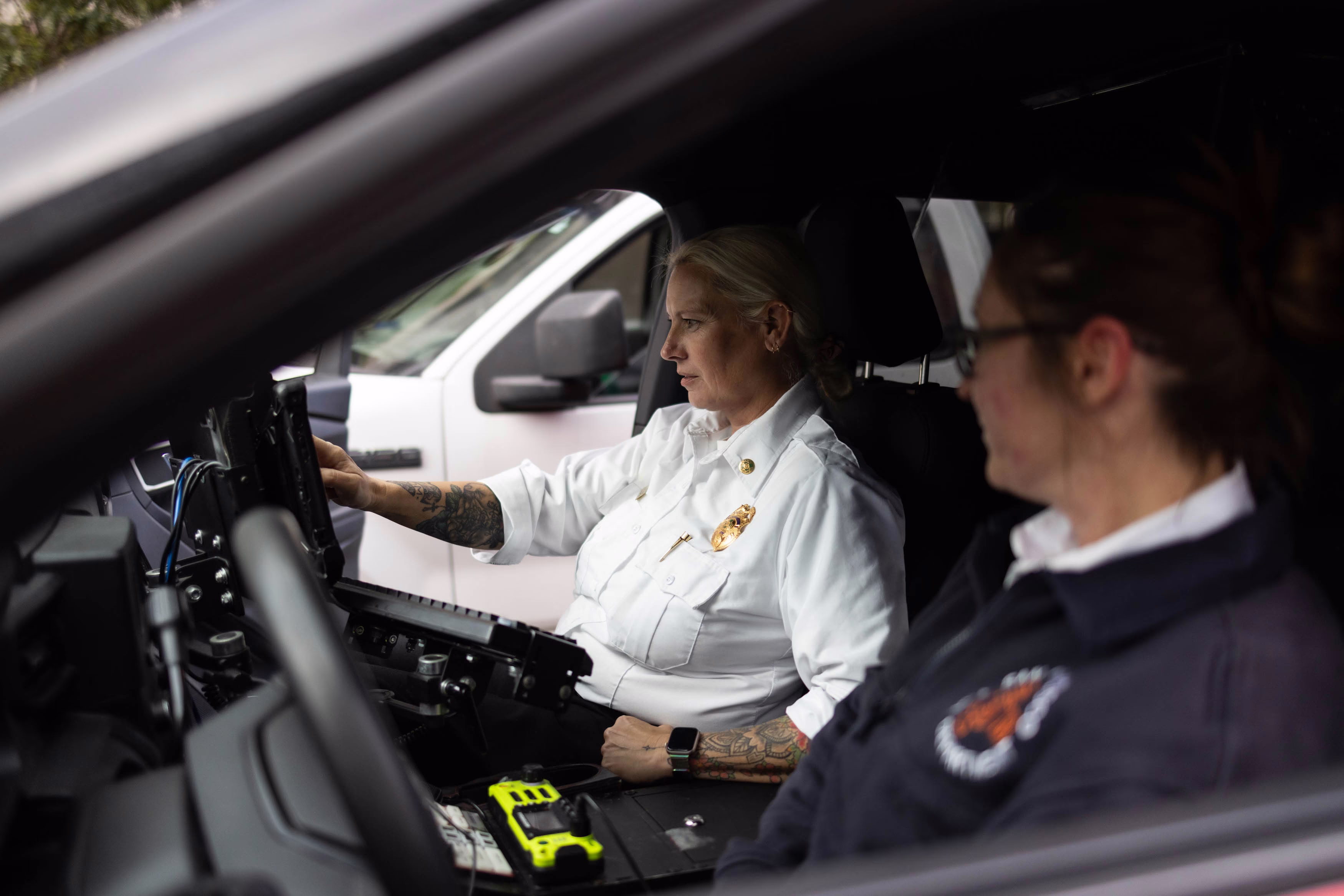 Picture of April Sloan and Sherry Mahoney inside the EMS6 vehicle in San Francisco, California, with Sloan checking a call monitor while Mahoney looks on during their shift.
