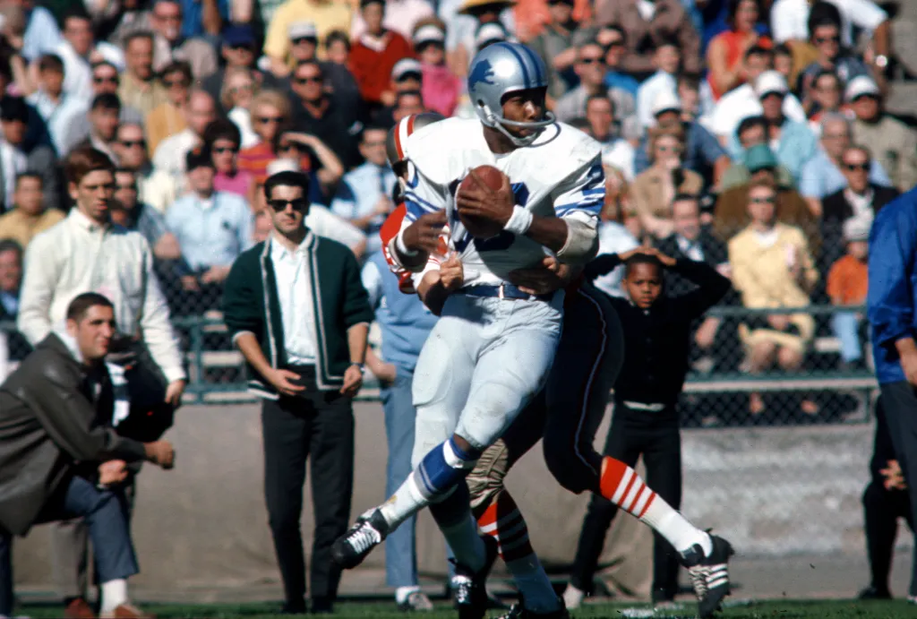 Detroit Lions player Lem Barney (20) being tackled by San Francisco 49ers player Sonny Randle (83) during a 1967 NFL game.