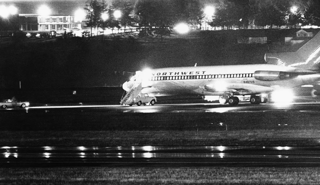 A Northwest Airlines jetliner N467US on a runway at night with a stair truck attached to a passenger door.
