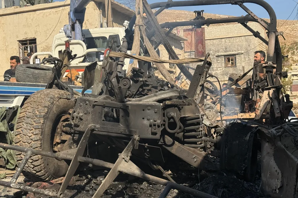 A crane removing a burnt Israeli Humvee from a street in the southern Syrian village of Beit Jin.