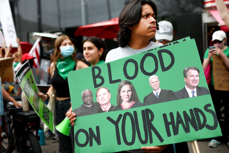 An abortion-rights activist holds a sign depicting Supreme Court Justices Clarence Thomas, Samuel A. Alito, Jr., Amy Coney Barrett, Neil M. Gorsuch, and Brett M. Kavanaugh during a demonstration outside a Planned Parenthood clinic as they safeguard the clinic from a possible protest by a far-right group on July 16, 2022 in Santa Monica, California.