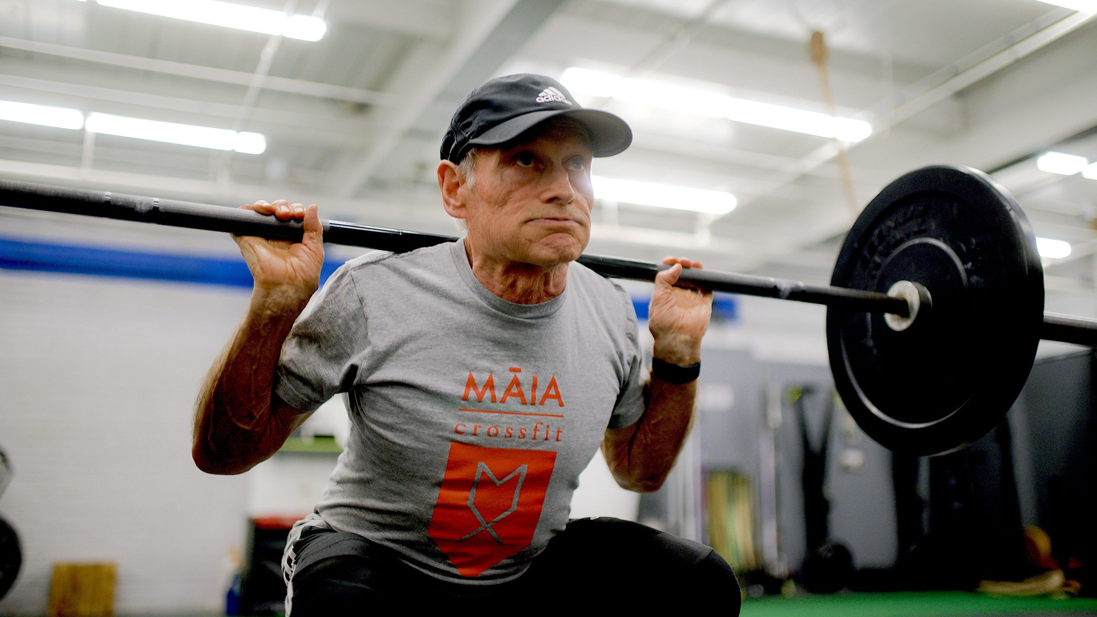 An older man lifting heavy weights.