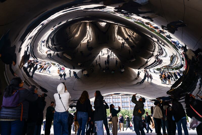 Reflection of tourists under Cloud Gate, known as The Bean,