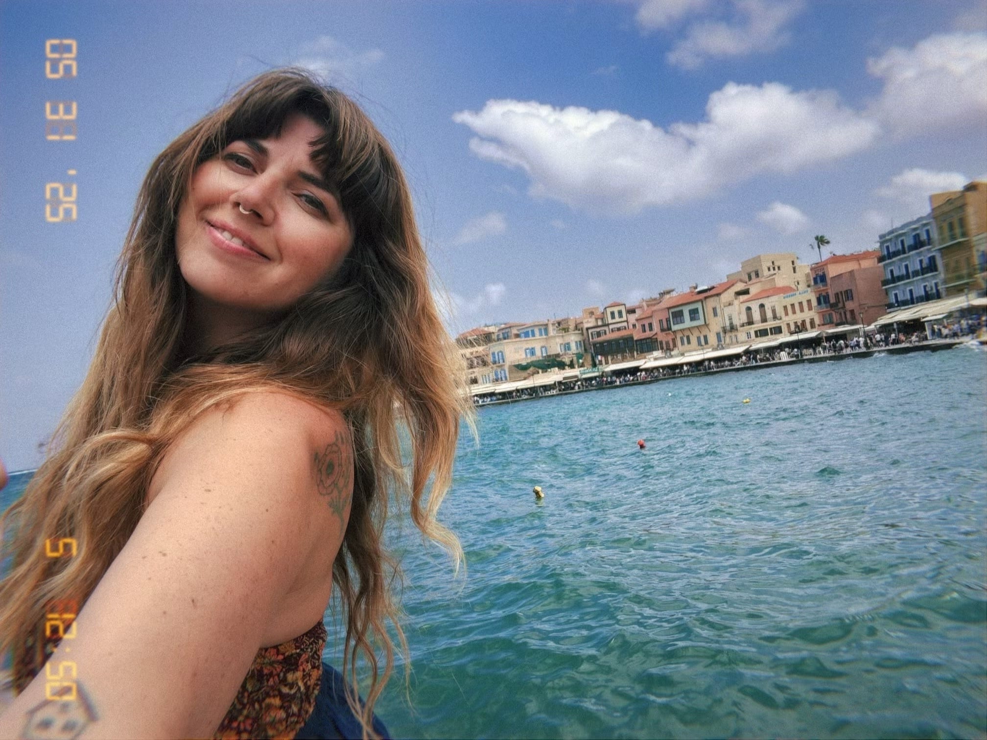 A woman posing in front of a body of water.