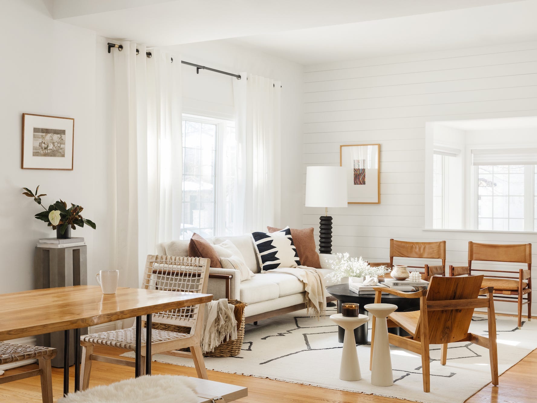 An open concept living room with a white couch and brown table.