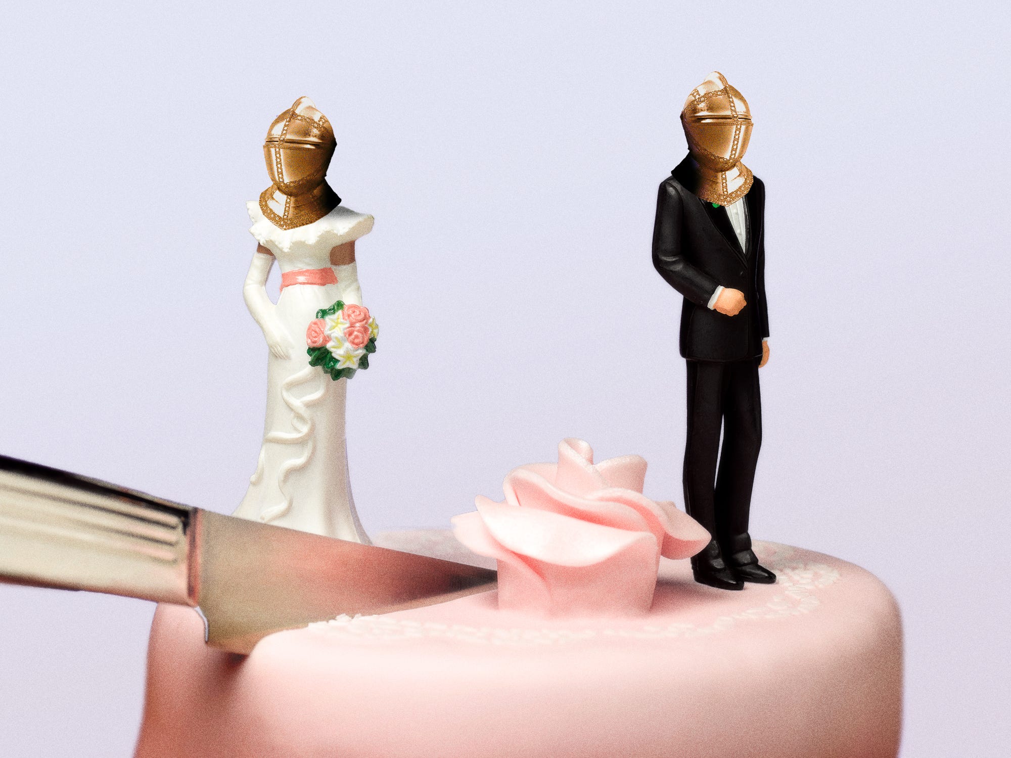 A close up of a wedding cake, with figurines that are separated by a knife both wearing helmets
