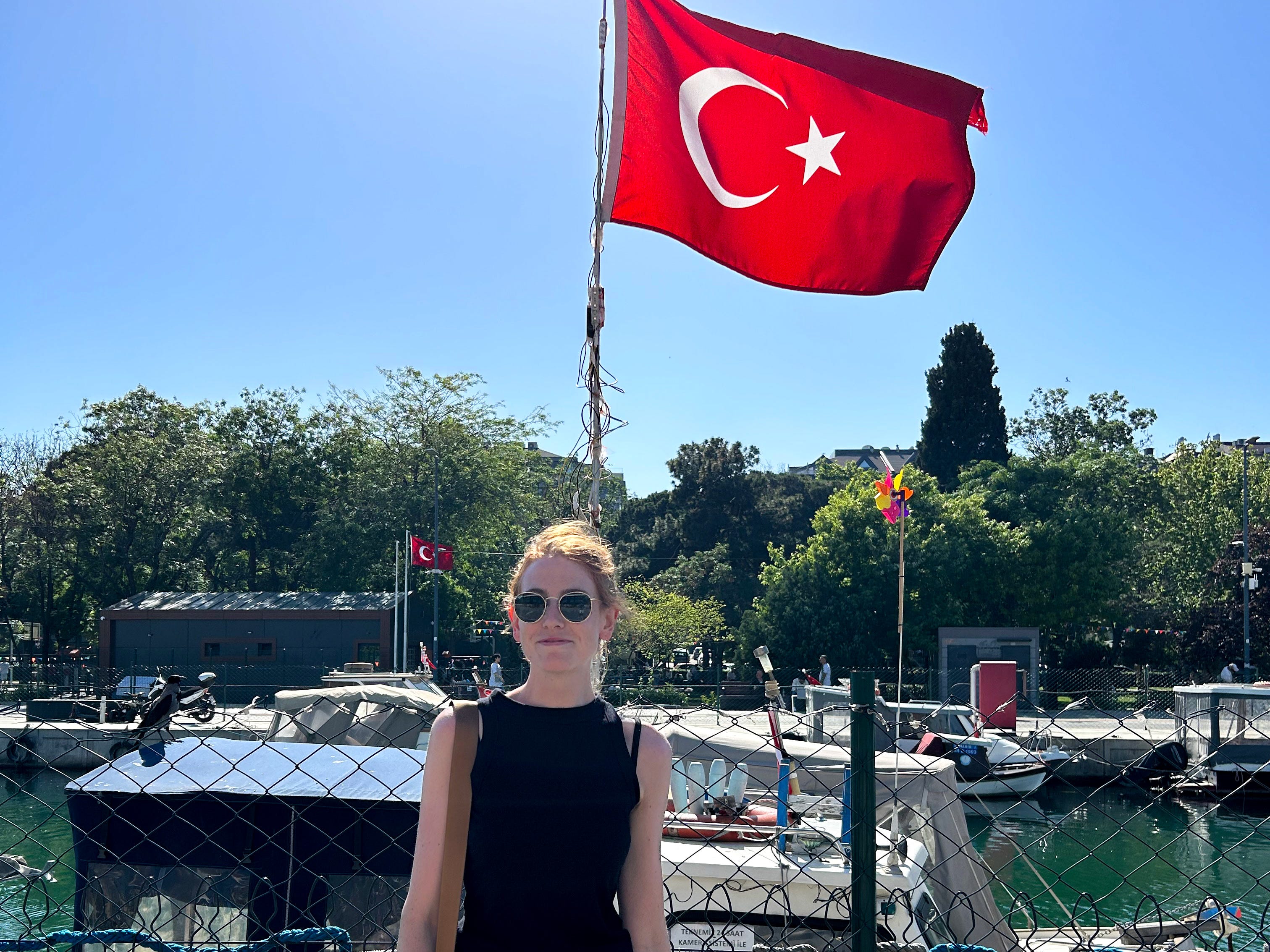 Kaitlyn stands in front of a Turkish flag by a river.