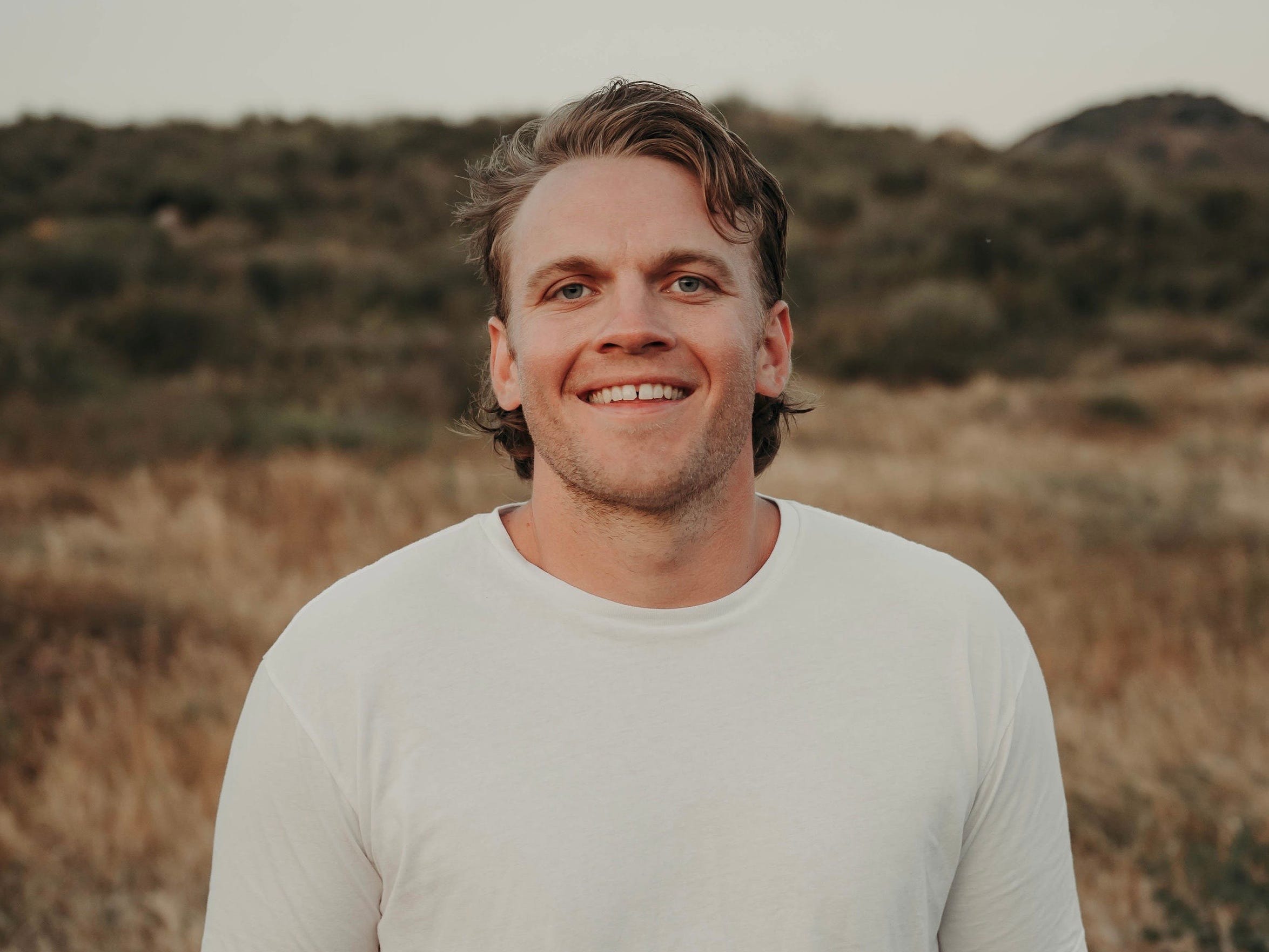 headshot of a man in a white t-shirt in a field