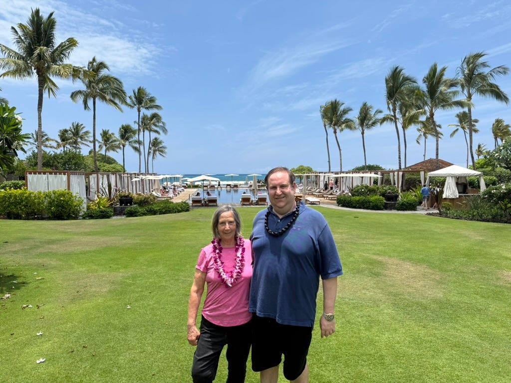 Author David Morris and woman standing in front of green grass, palm trees