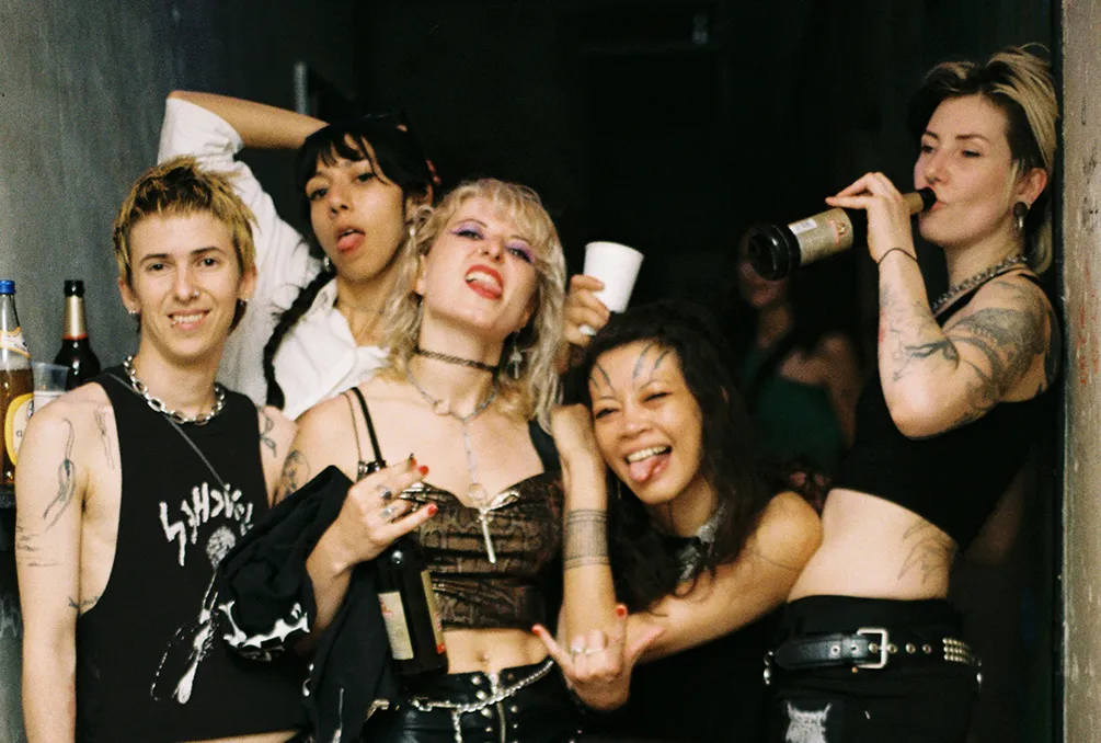 A group of young women pose for the camera while drinking alcohol at a punk rock show in Berlin