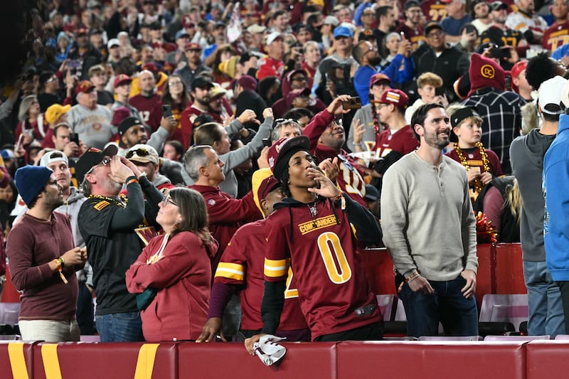 People react as unseen US President Donald Trump appears onscreen during the NFL game between the Washington Commanders and the Detroit Lions at Northwest Stadium in Landover, Maryland, on November 9, 2025. (Photo by Mandel NGAN / AFP) (Photo by MANDEL NGAN/AFP via Getty Images)