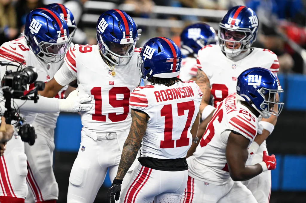 New York Giants players huddle on the field.