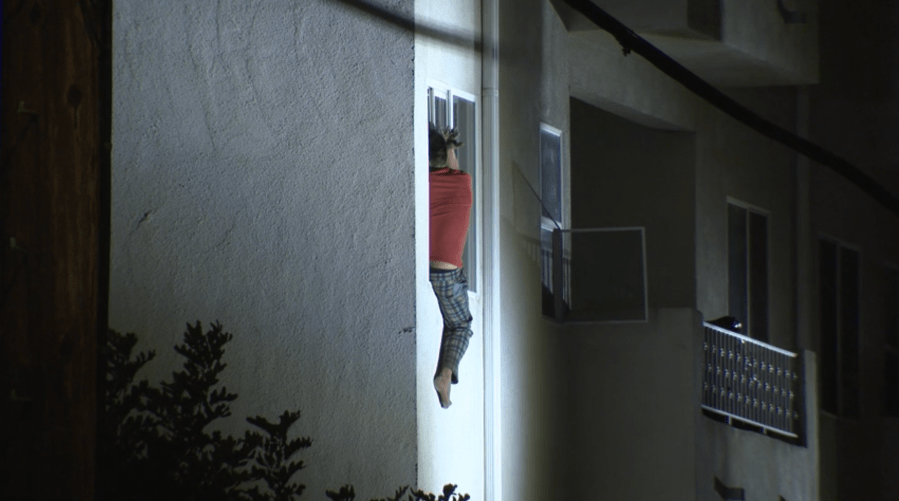 Man throwing items in L.A. apartment building hangs out of window 
