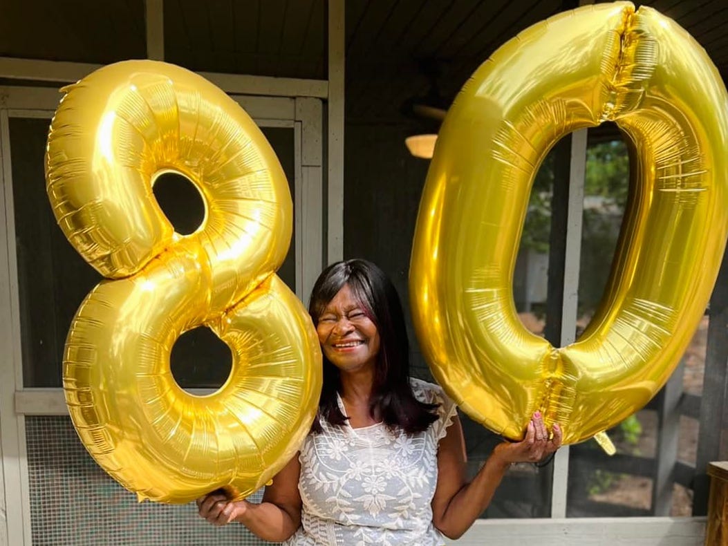 Janelle Jones' grandmother holding balloons that say 80