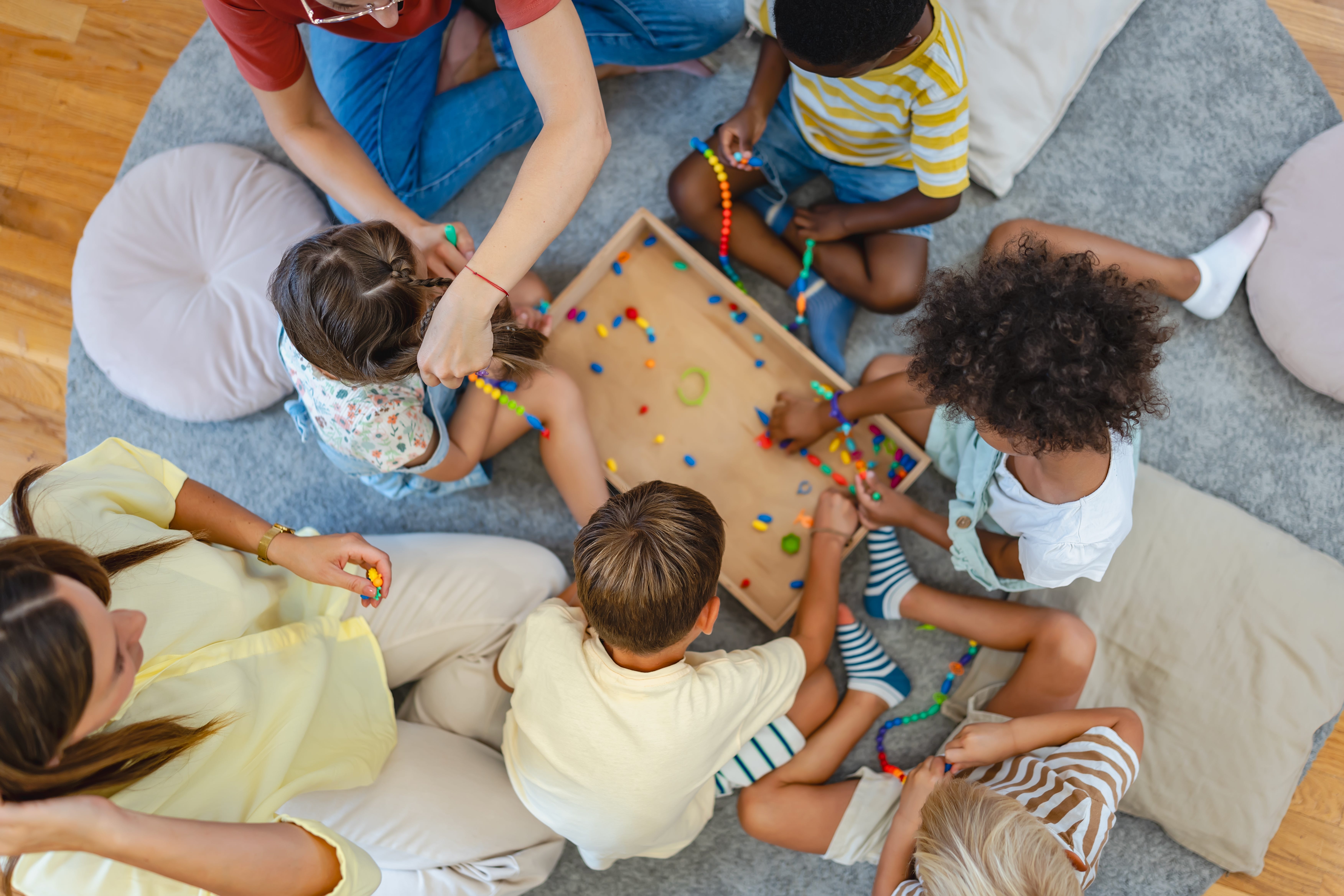 Top-down view of preschool kids using beads