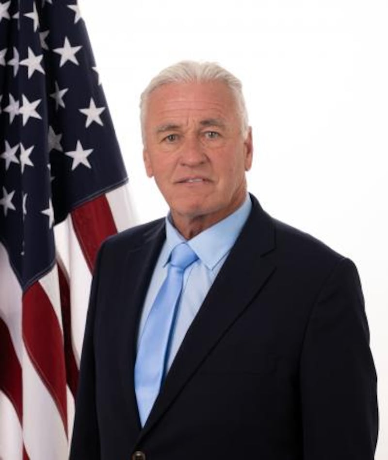 Dr. George Tidmarsh stands in front of an American flag.
