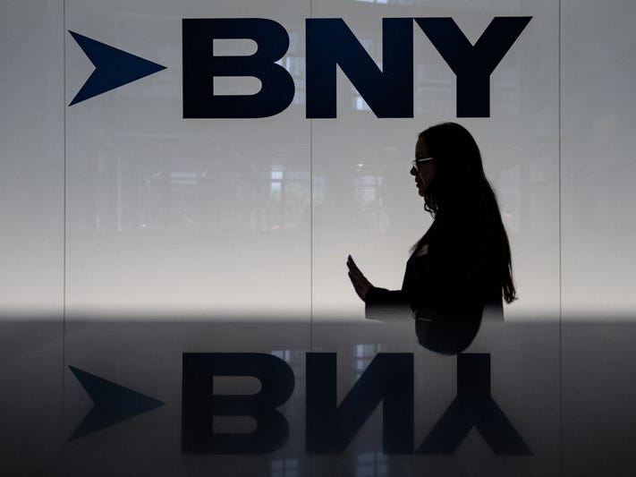 A woman walking in front of the BNY logo.