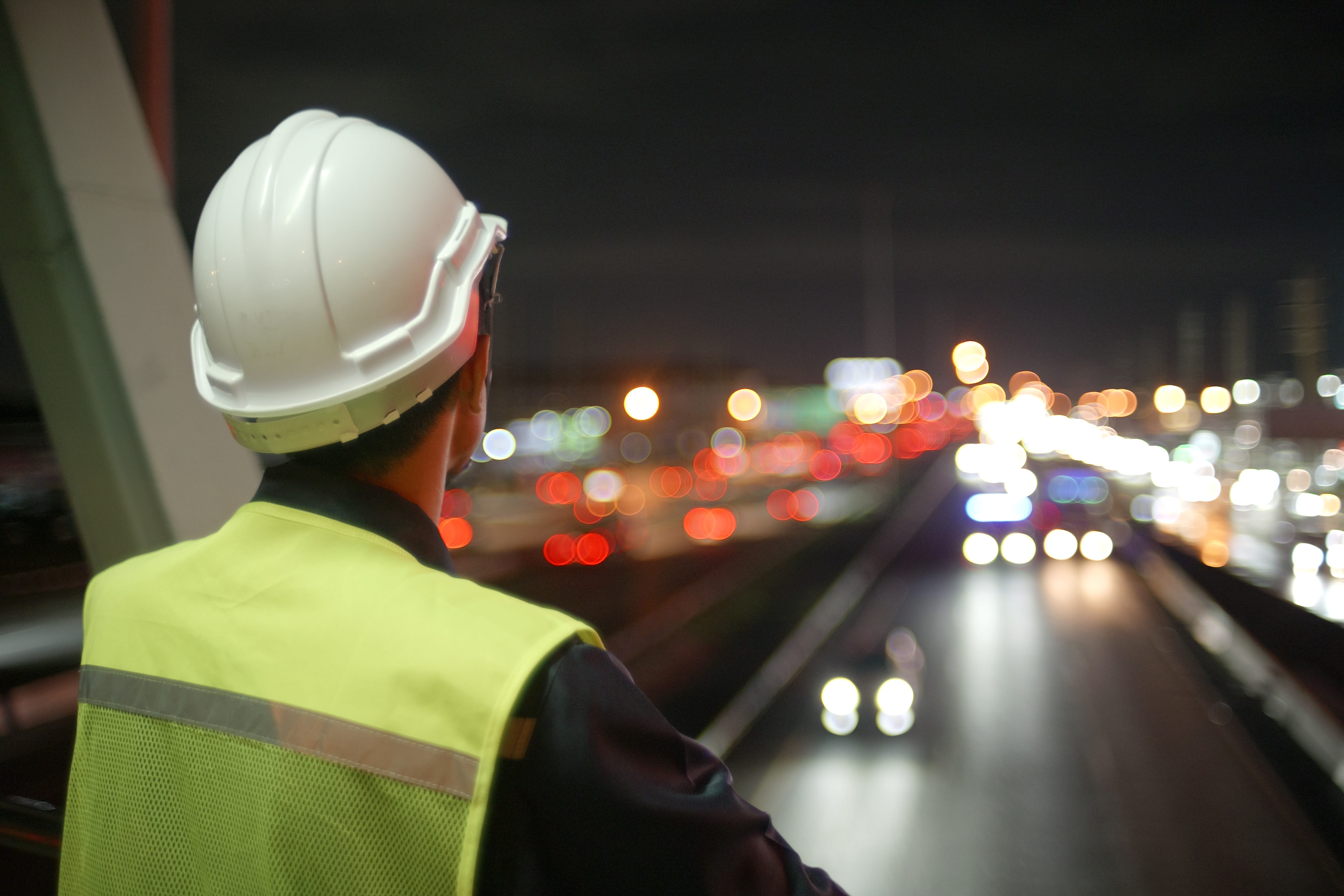 Construction worker standing on a bridge at night