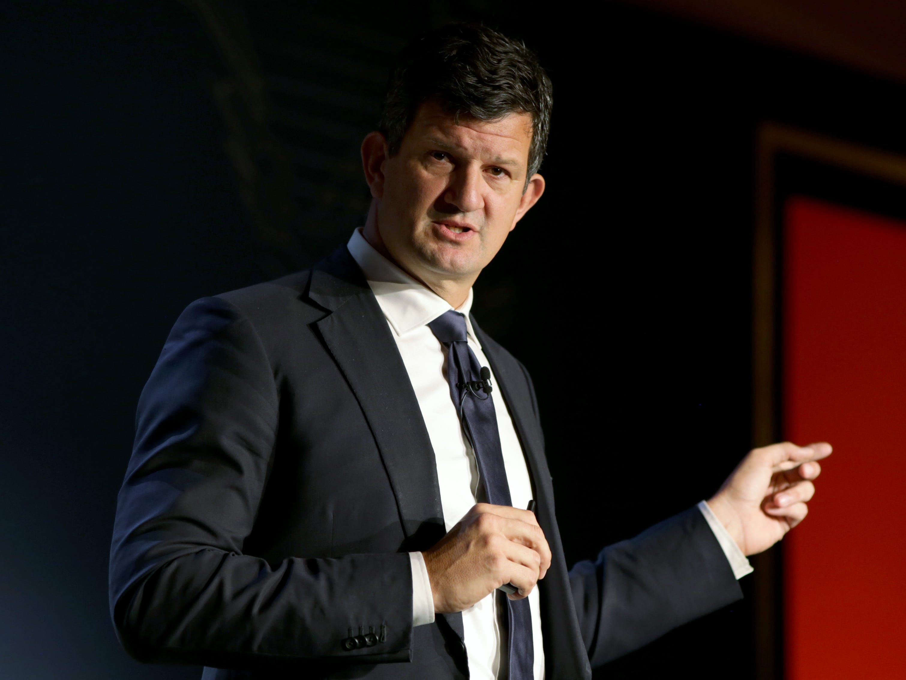 Steve Hasker points with his finger on a stage.