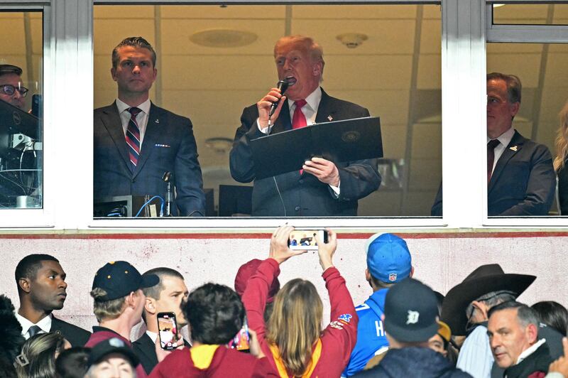 President Donald Trump, alongside Defense Secretary Pete Hegseth reads the oath for people reenlisting to the U.S. army as he attends the NFL game between the Washington Commanders and the Detroit Lions.