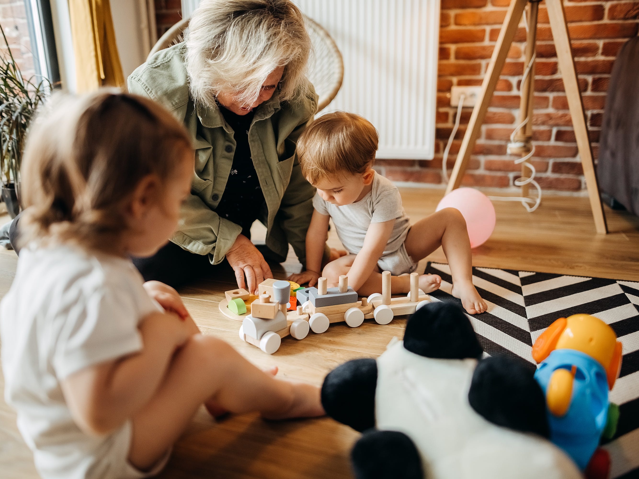 A grandmother playing with her grandkids on the floor.