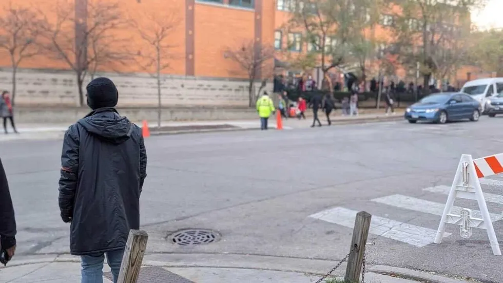 A volunteer with Rogers Park School Patrols watches a school 
