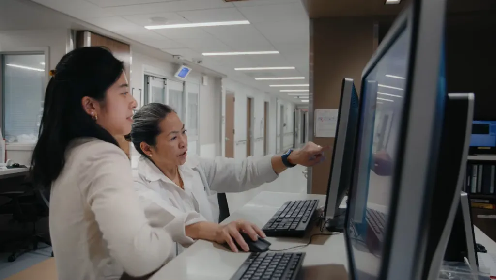 Two medical professionals reviewing patient data on a computer.