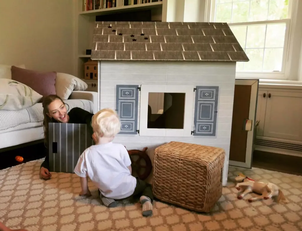 Amanda Seyfried with her son playing in front of a toy house.