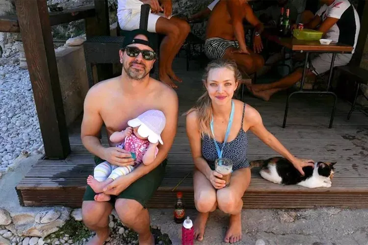 Amanda Seyfried with her husband and child, petting a cat.