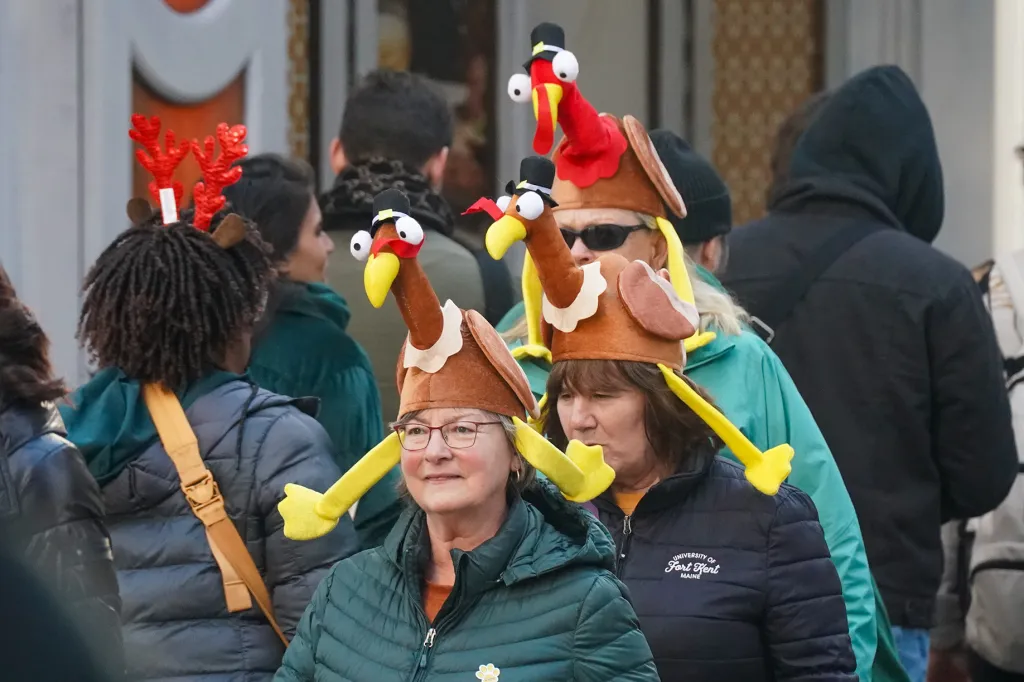 People with turkey hats walk down the parade route. 