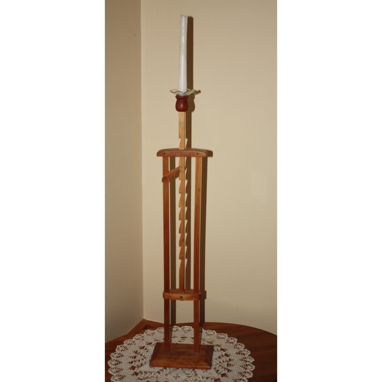 A wooden candle stand with a white candle in it. 