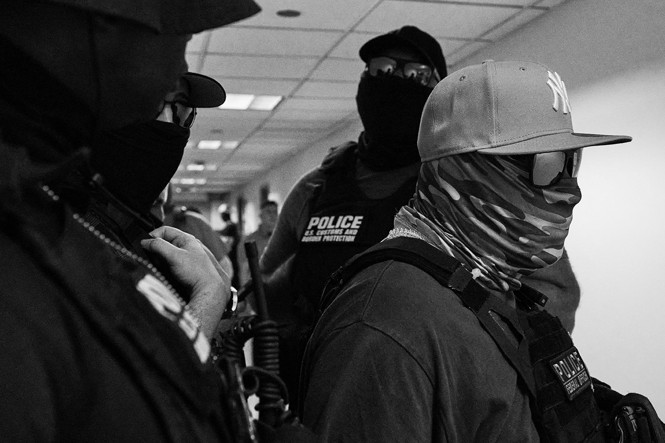 four people wearing police vests and wearing hats sunglasses and face masks