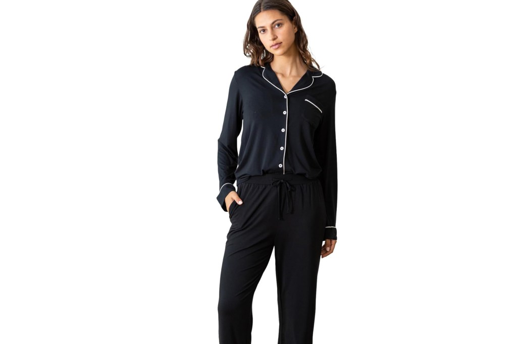 A woman models black pajamas with white piping.