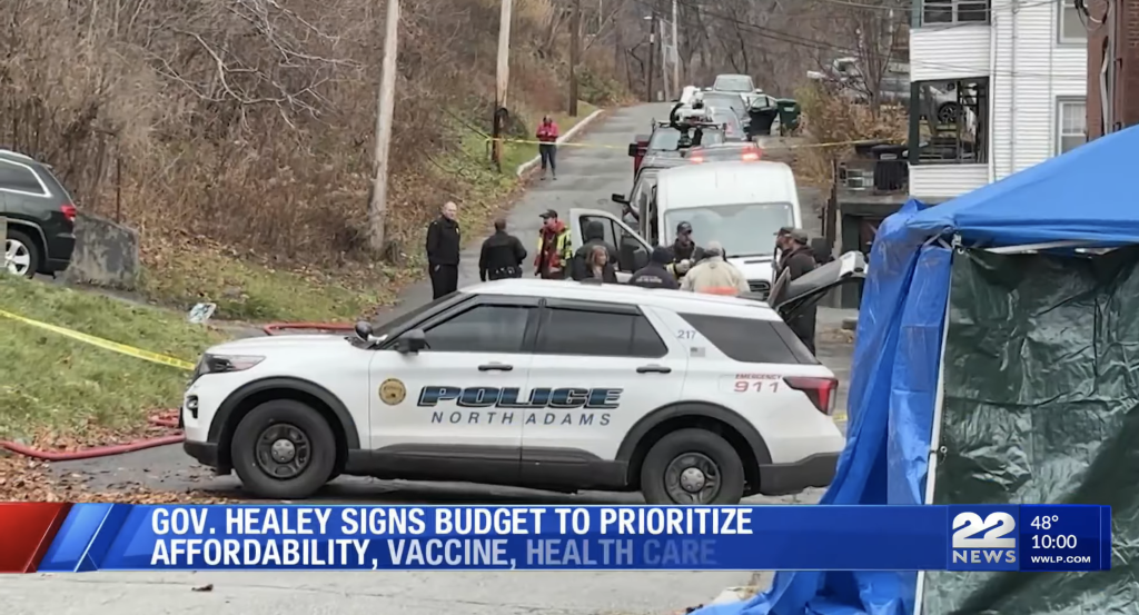 North Adams police car at the scene of a fire on Francis Street, with a blue tent in the foreground and a house with a damaged window in the background.