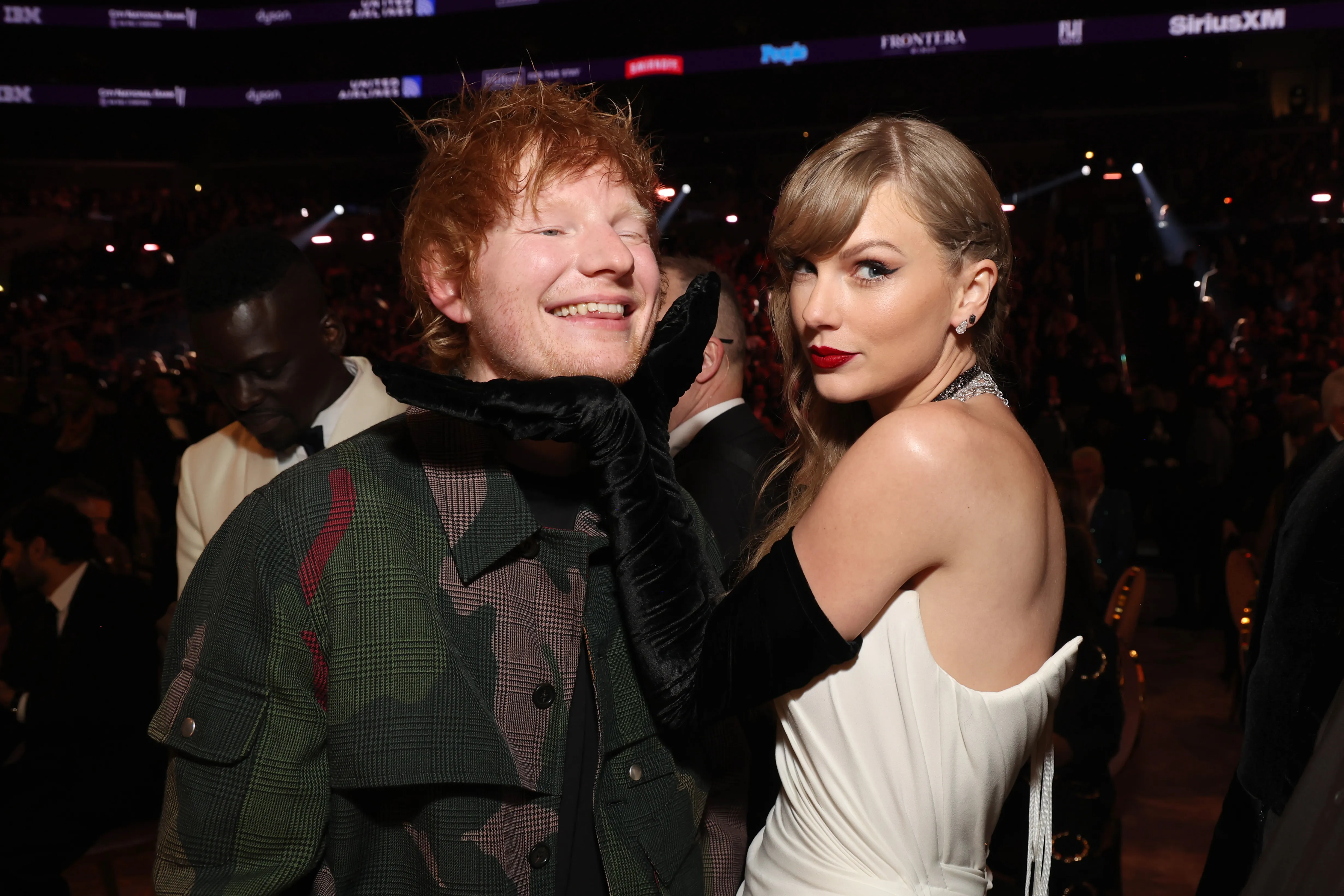 Taylor Swift with a black-gloved hand under Ed Sheeran’s chin.