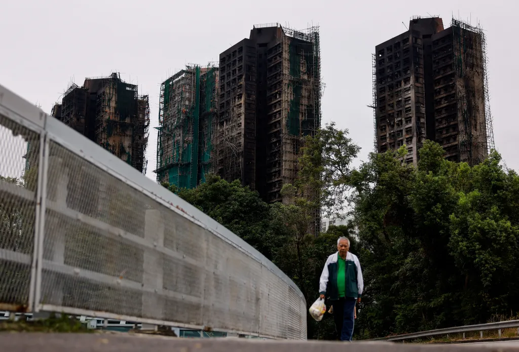 A man walks away from the burned building of Wang Fuk Court housing complex in Tai Po, Hong Kong.