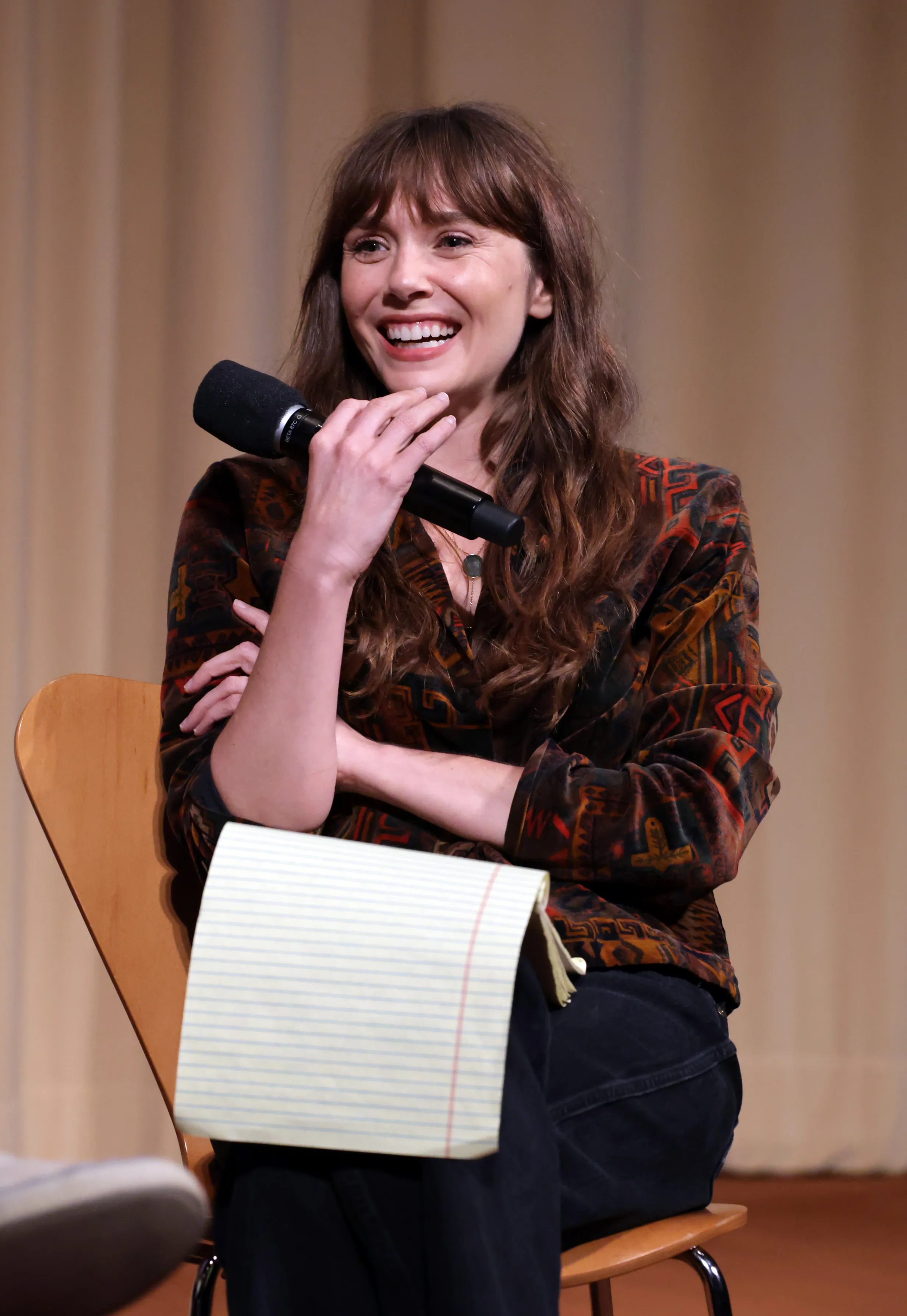 Elizabeth Olsen smiling and holding a microphone at a special screening of 