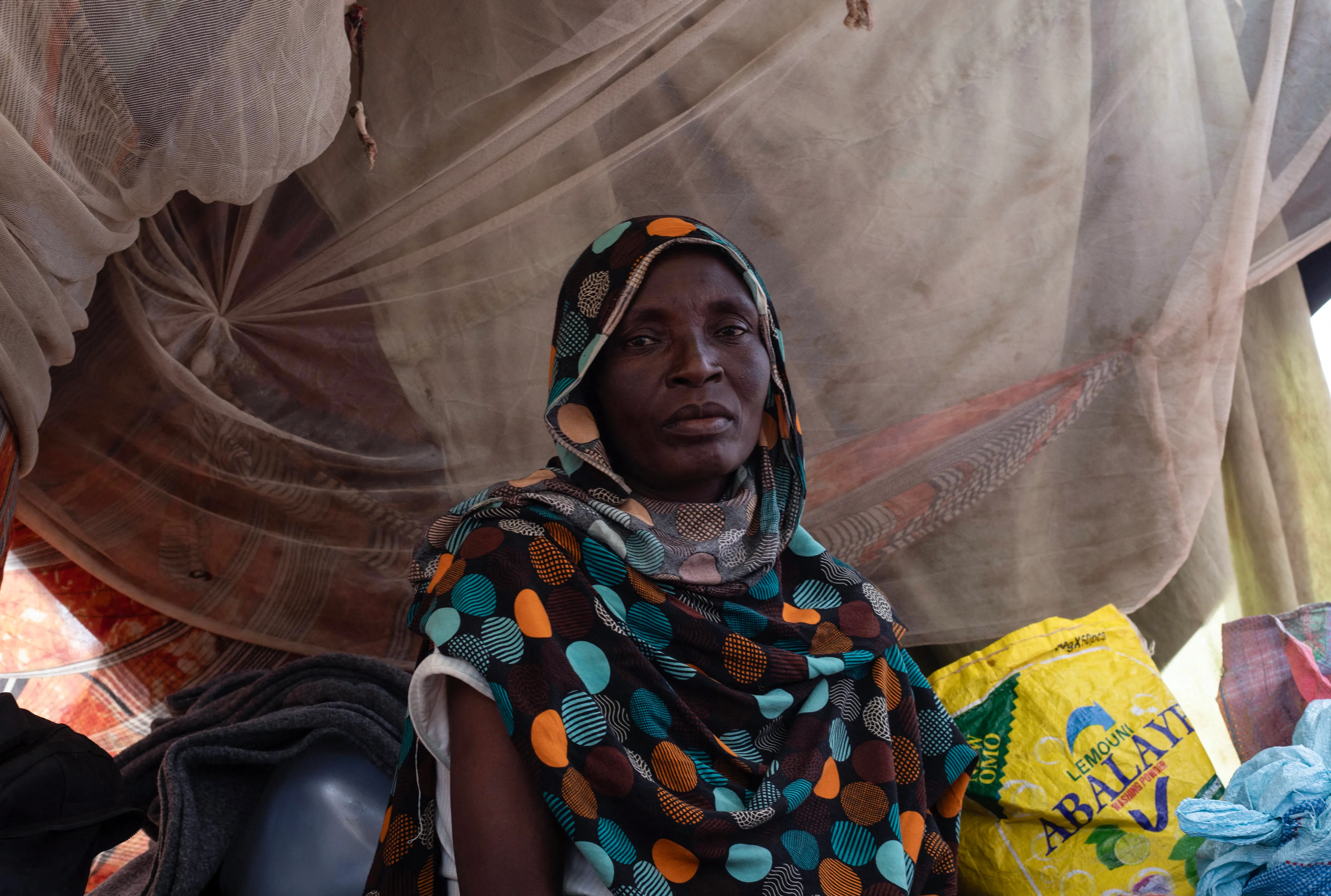 A woman sits in a makeshift tent A woman sits in a makeshift tent