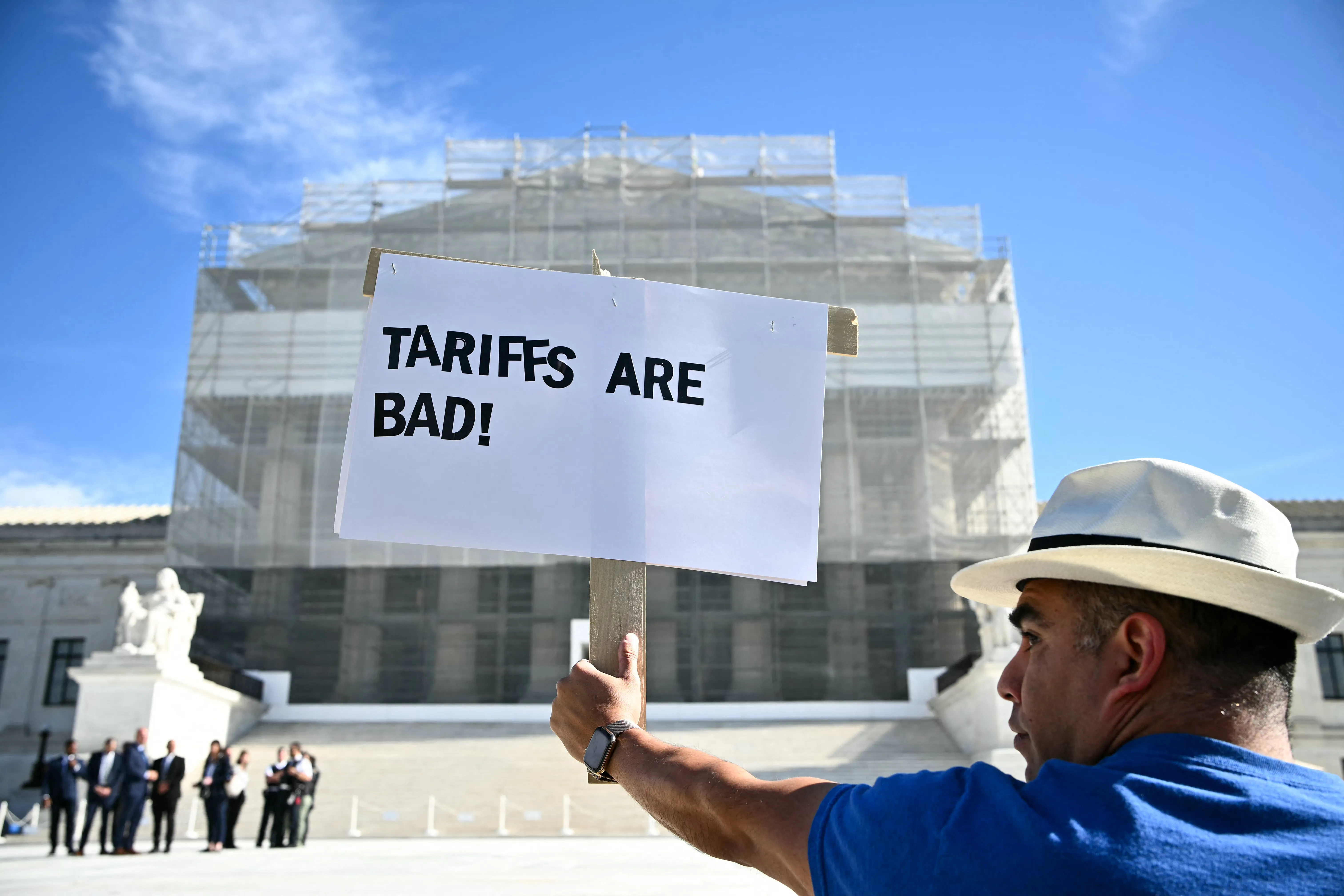 A protester holding up a “tariffs are bad” sign outside the Supreme Court.